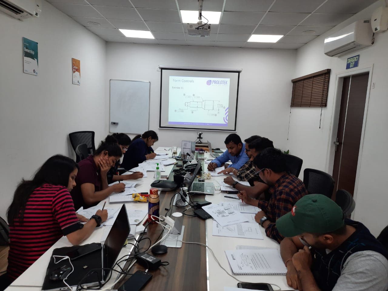 Learners taking notes during a classroom training session with a presentation on screen